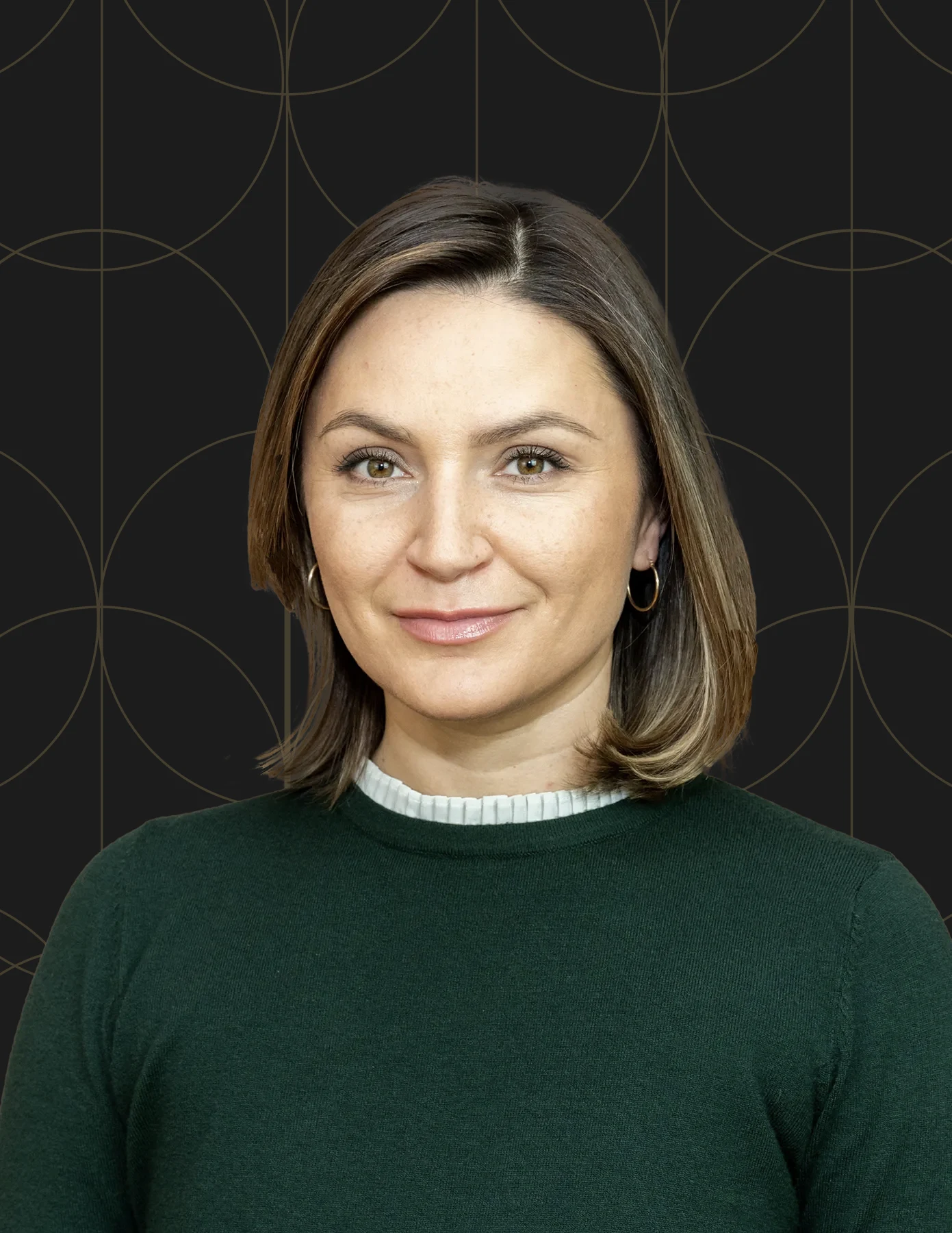 hmg-plus-team-member-headshot-brunette-green-sweater-hmg-plus. Professional headshot of a woman with a dark brown bob wearing a forest green sweater.